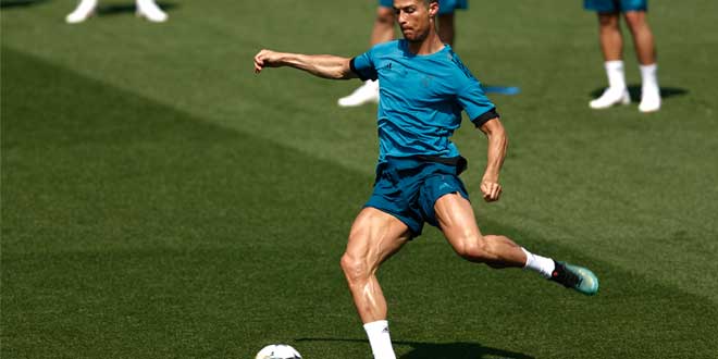 Fußballspieler trainiert auf dem Rasenplatz und schießt den Ball während einer Trainingseinheit.