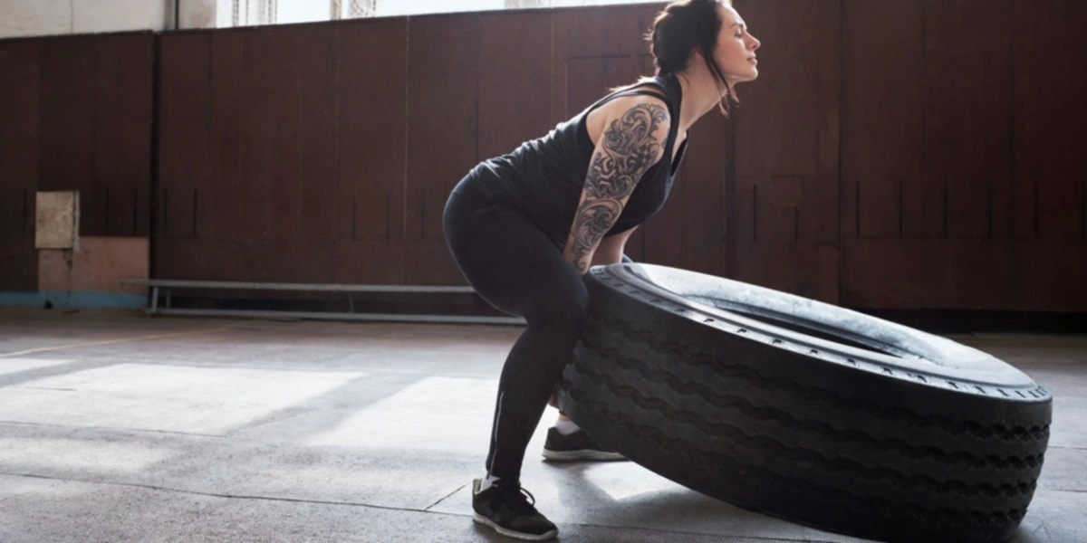 Mujer entrenando levanta una rueda de camión
