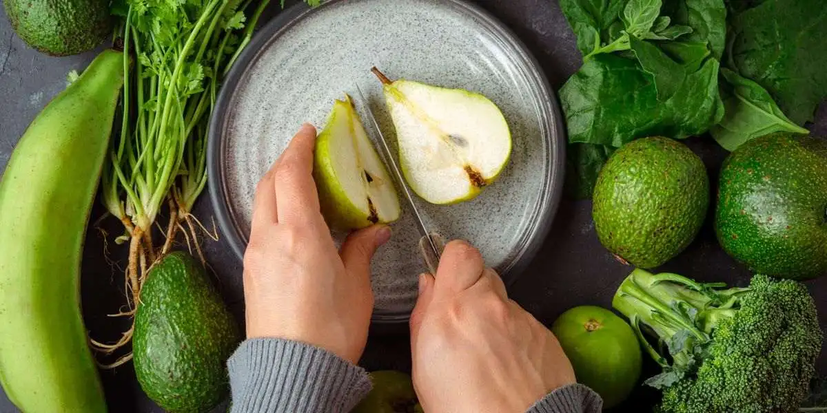 Couper une poire entourée d’avocats, brocoli et bananes