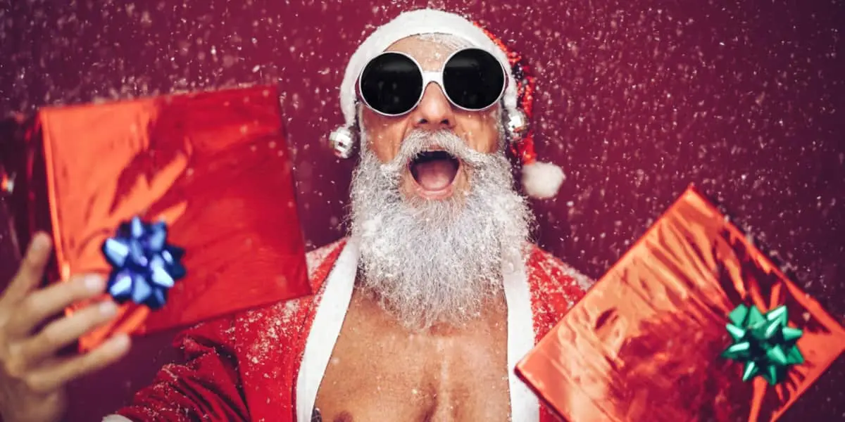 Fit Santa Claus holding gifts and wearing sunglasses