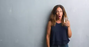 Mujer sorprendida bebiendo un vaso de agua con sal de magnesio