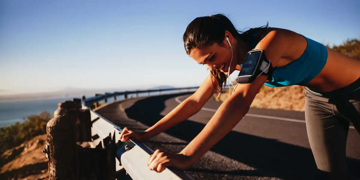 Femme coureuse arrêtée au milieu de la route en train de se reposer Femme coureuse arrêtée au milieu de la route en train de se reposer