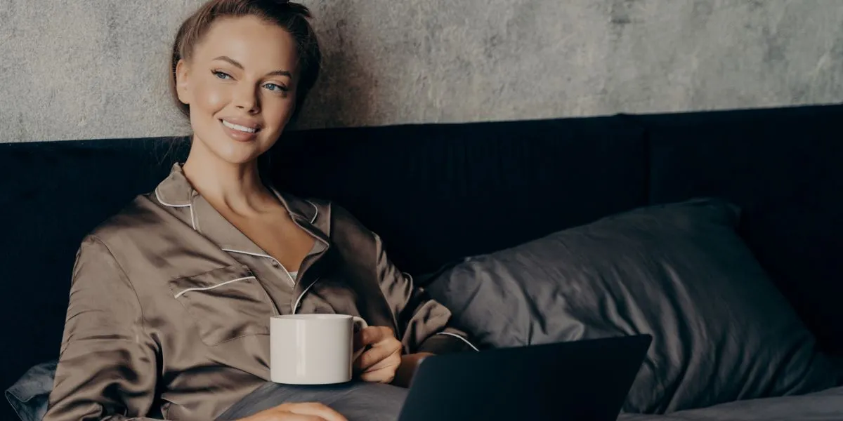 Mujer joven convaleciente reposando en la cama tomando te