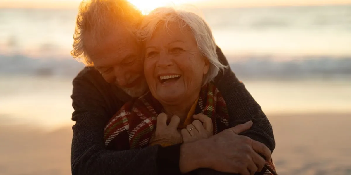 Couple senior souriant en marchant sur la plage