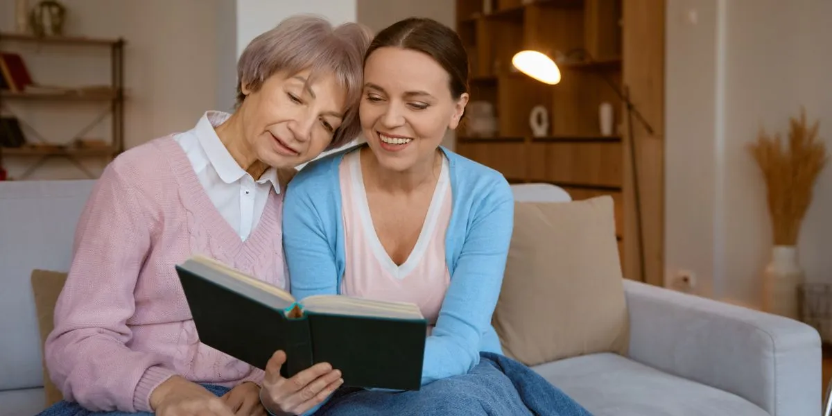 Mère et fille assises sur le canapé consultant le guide