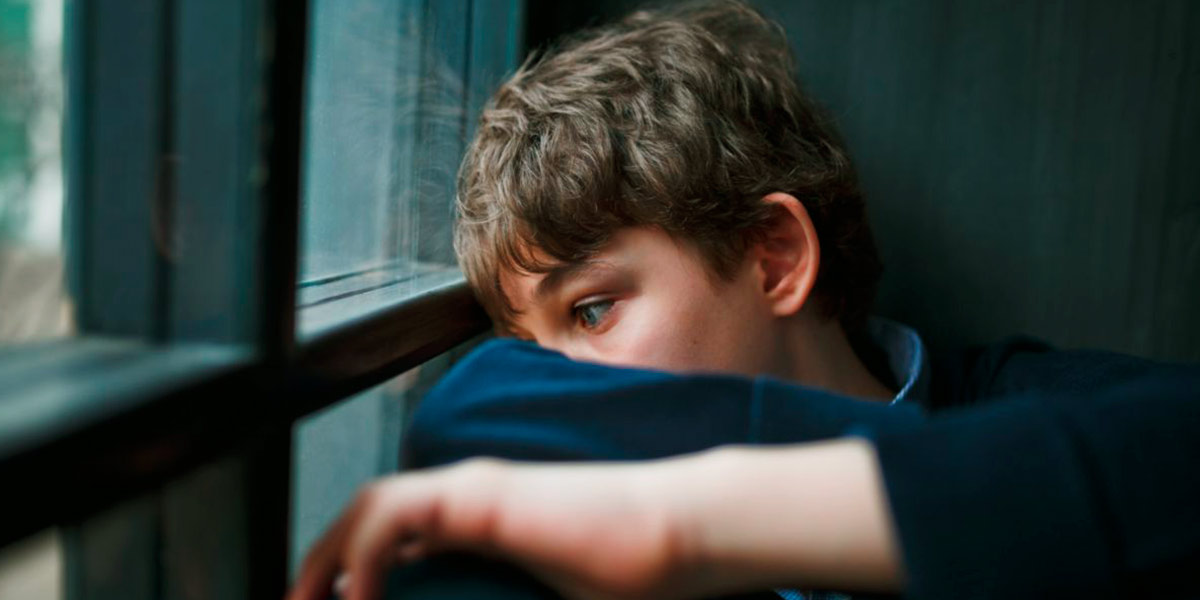 adolescente chiuso in casa che guarda fuori dalla finestra