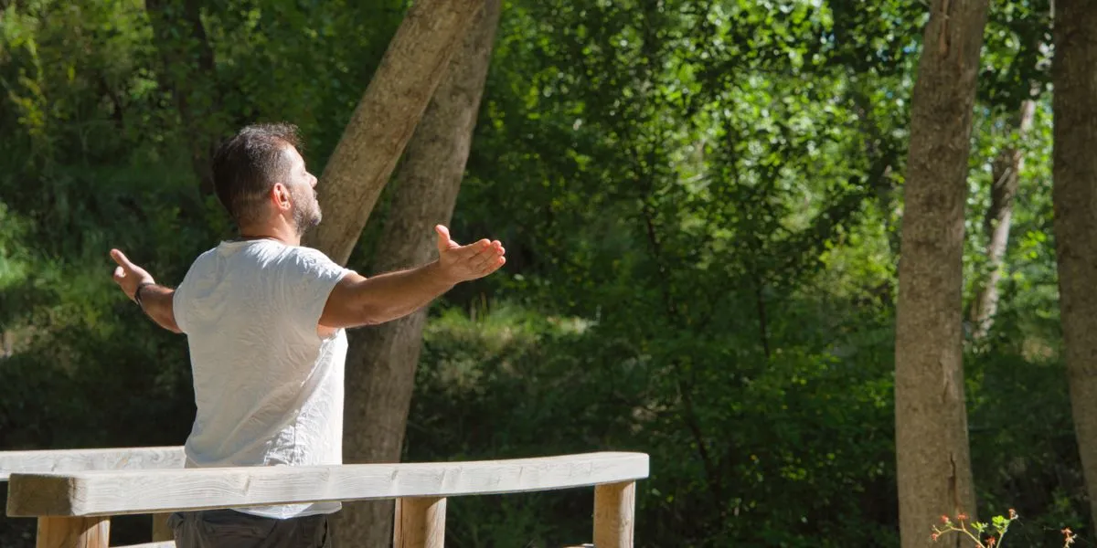 Hombre en el bosque practicando la respiración profunda para reducir el estrés y mantener la energía Hombre en el bosque practicando la respiración profunda para reducir el estrés y mantener la energía