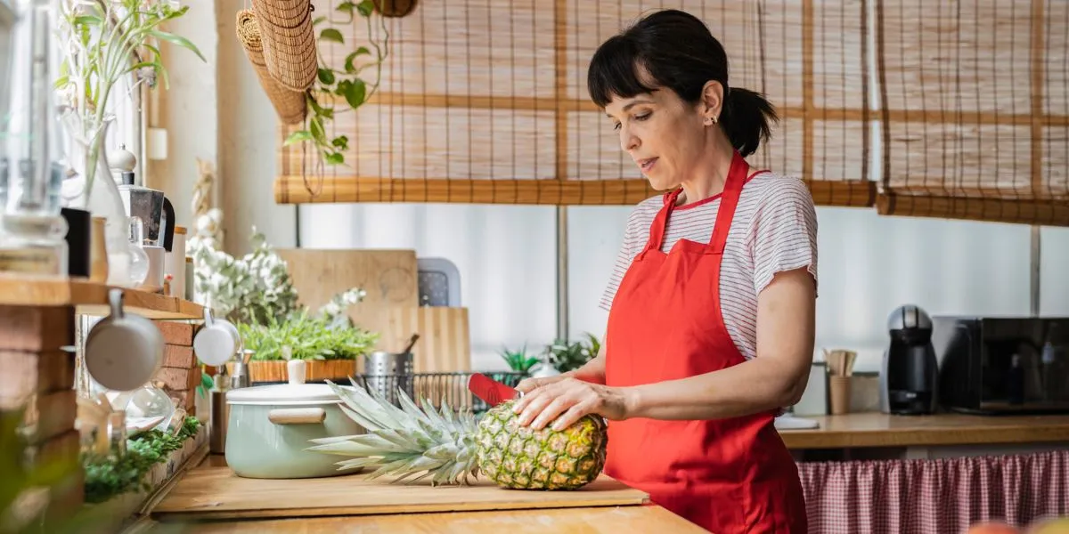 Mujer en la cocina pelando una piña