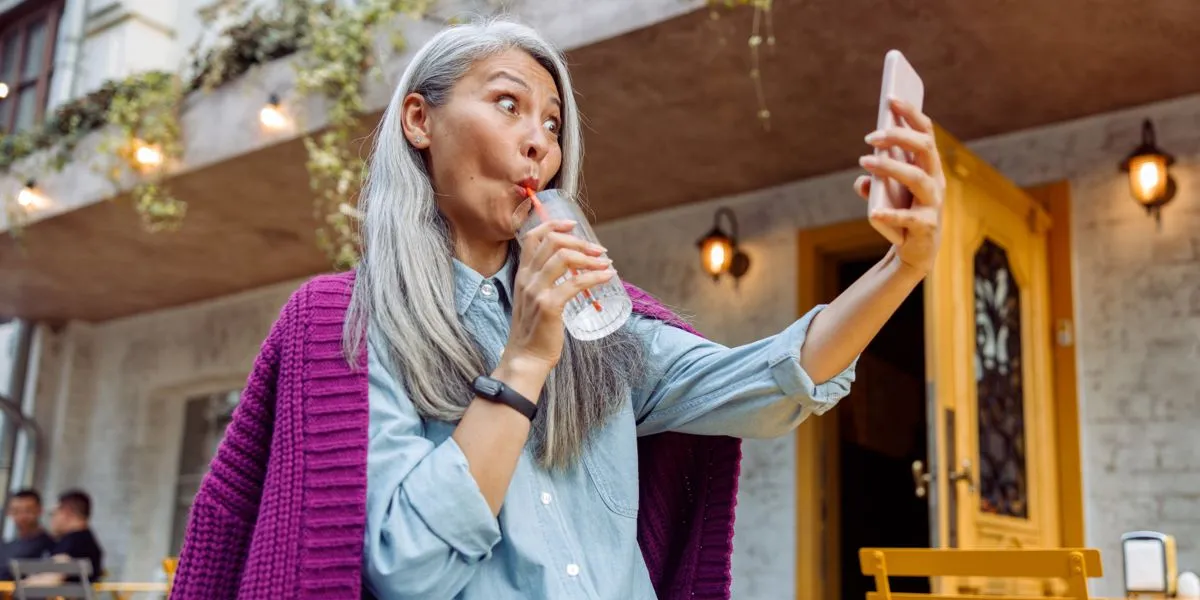 Mujer bebiendo agua mientras se toma un selfie