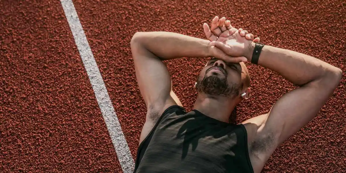 Athlète allongé sur la piste d'athlétisme avec des signes évidents de manque d'énergie