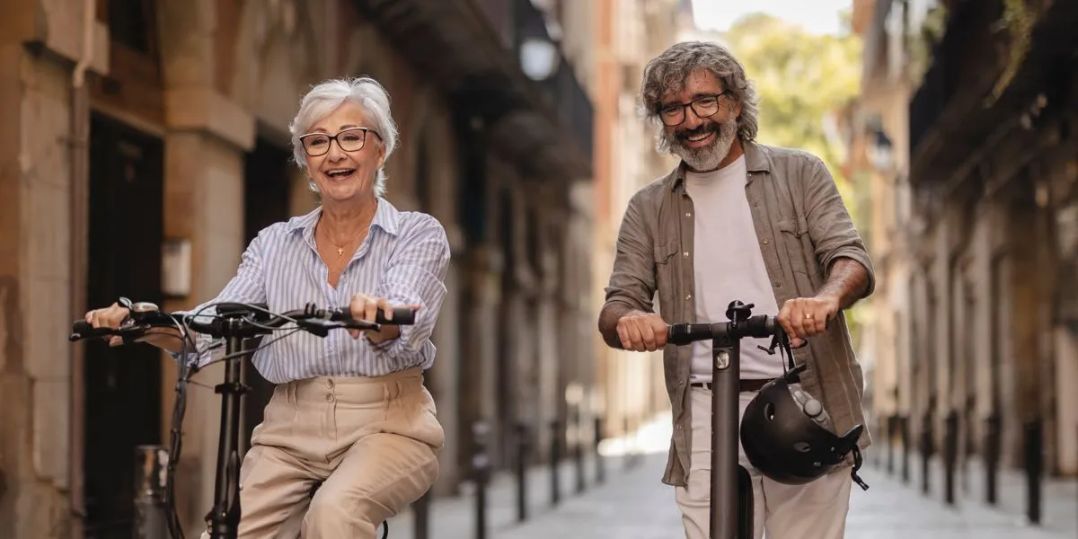 Coppia anziana che si diverte in monopattino e bici elettrica Coppia anziana che si diverte in monopattino e bici elettrica