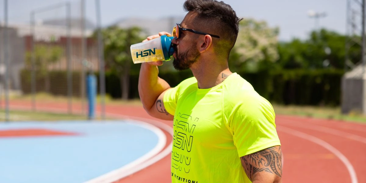 Corredor en pista de atletismo bebiendo bebida isotónica