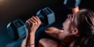 Mujer realizando press de pecho con mancuernas