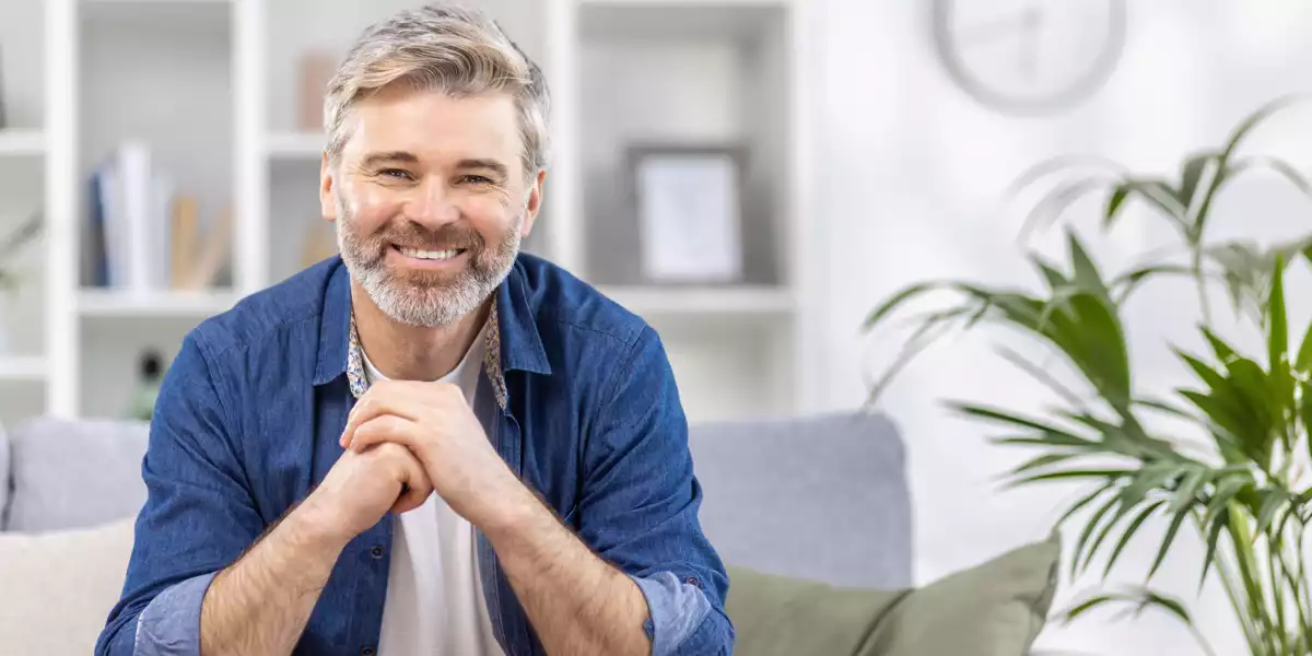 Glücklicher Mann sitzt auf dem Sofa
