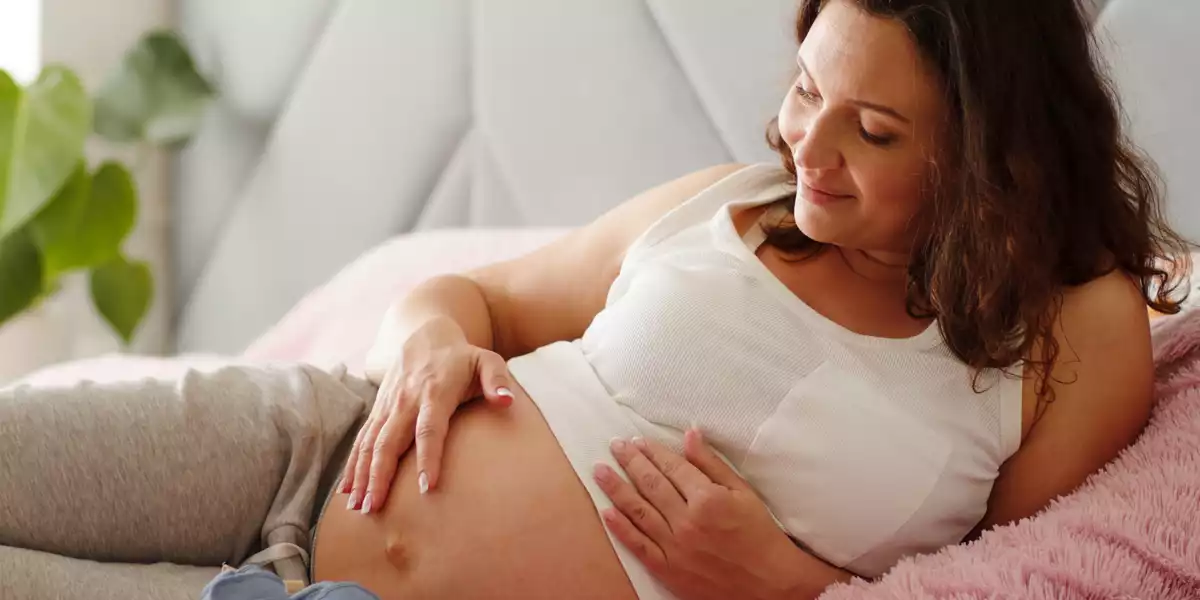 Happy pregnant woman lying on bed