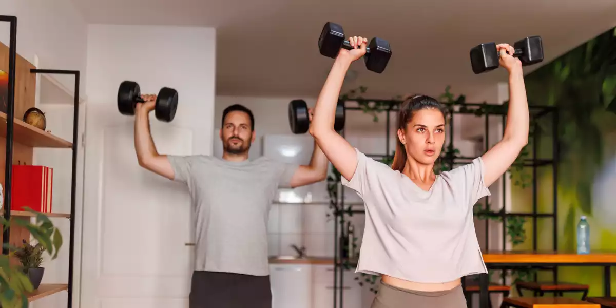 Pareja entrenando con mancuernas en su casa