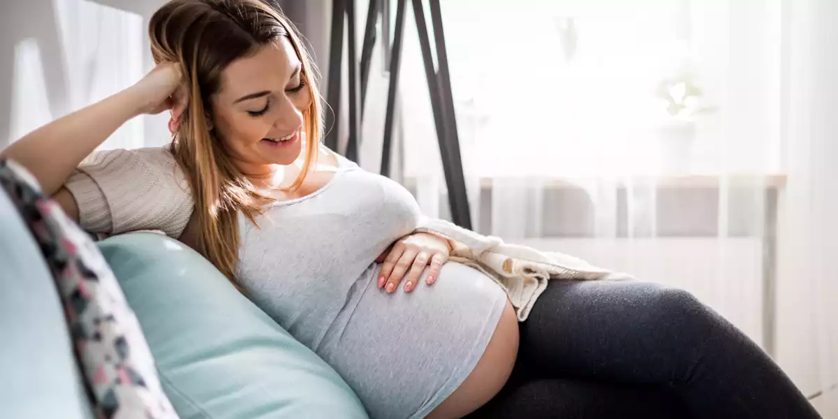Femme enceinte se reposant sur le canapé en souriant